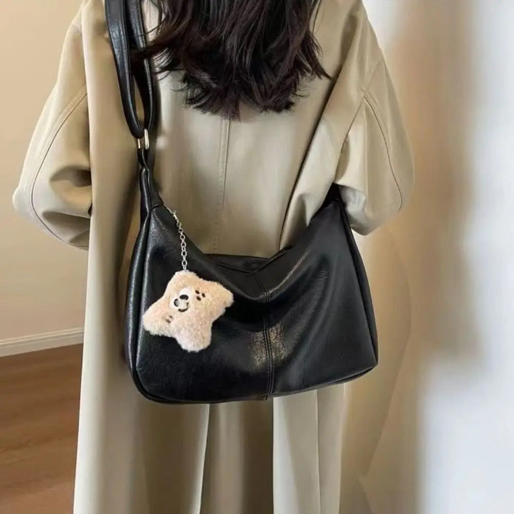 Detalle del bolso hobo Lena en negro con su colgante